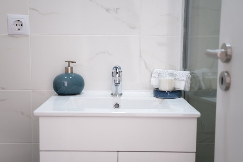 pexels-photo-18071802-18071802 A clean, modern bathroom setup with a white sink, chrome faucet, soap dispenser, and towels.