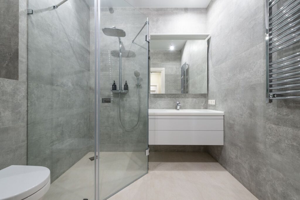 Creative design of bathroom with toilet bowl and washbasin under mirror against rack on tiled wall in house